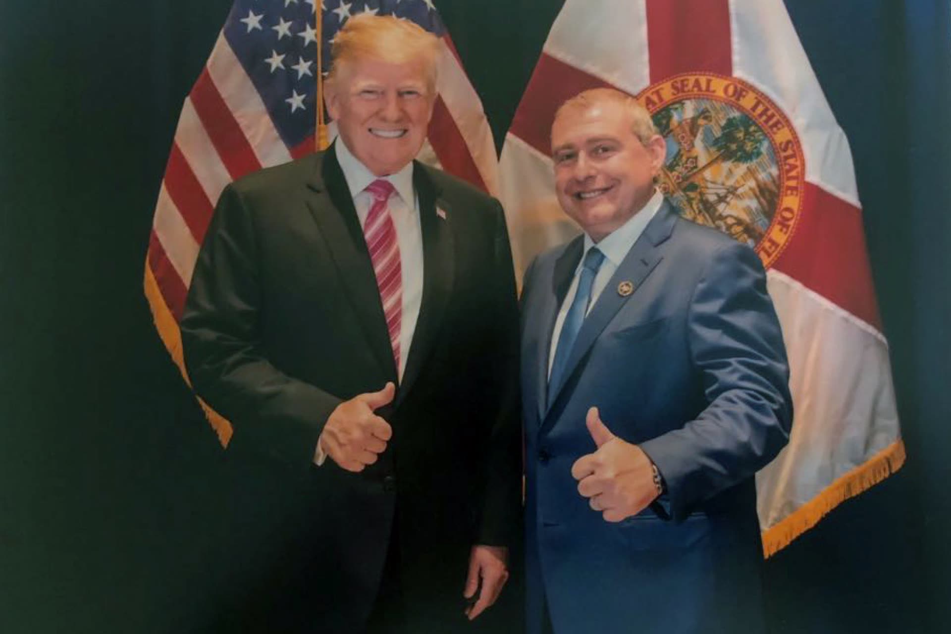 Lev Parnas and Donald Trump giving a thumbs up in front of the Florida flag